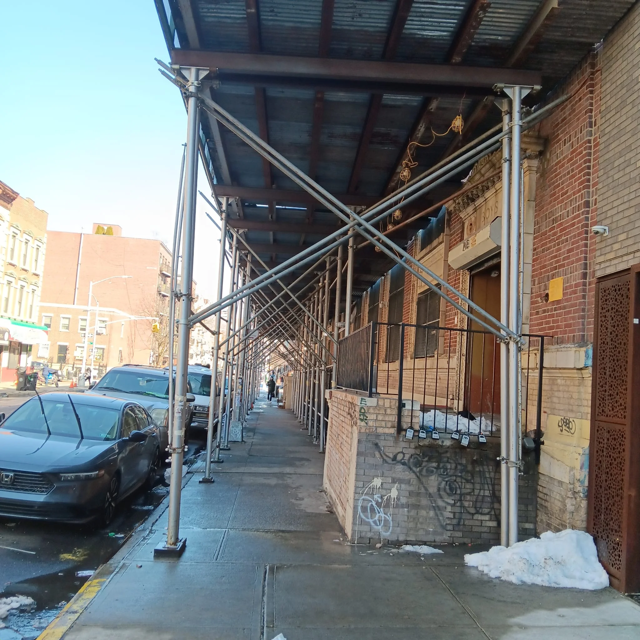 Sidewalk shed scaffolding along a building in Queens, NY, providing pedestrian safety during construction