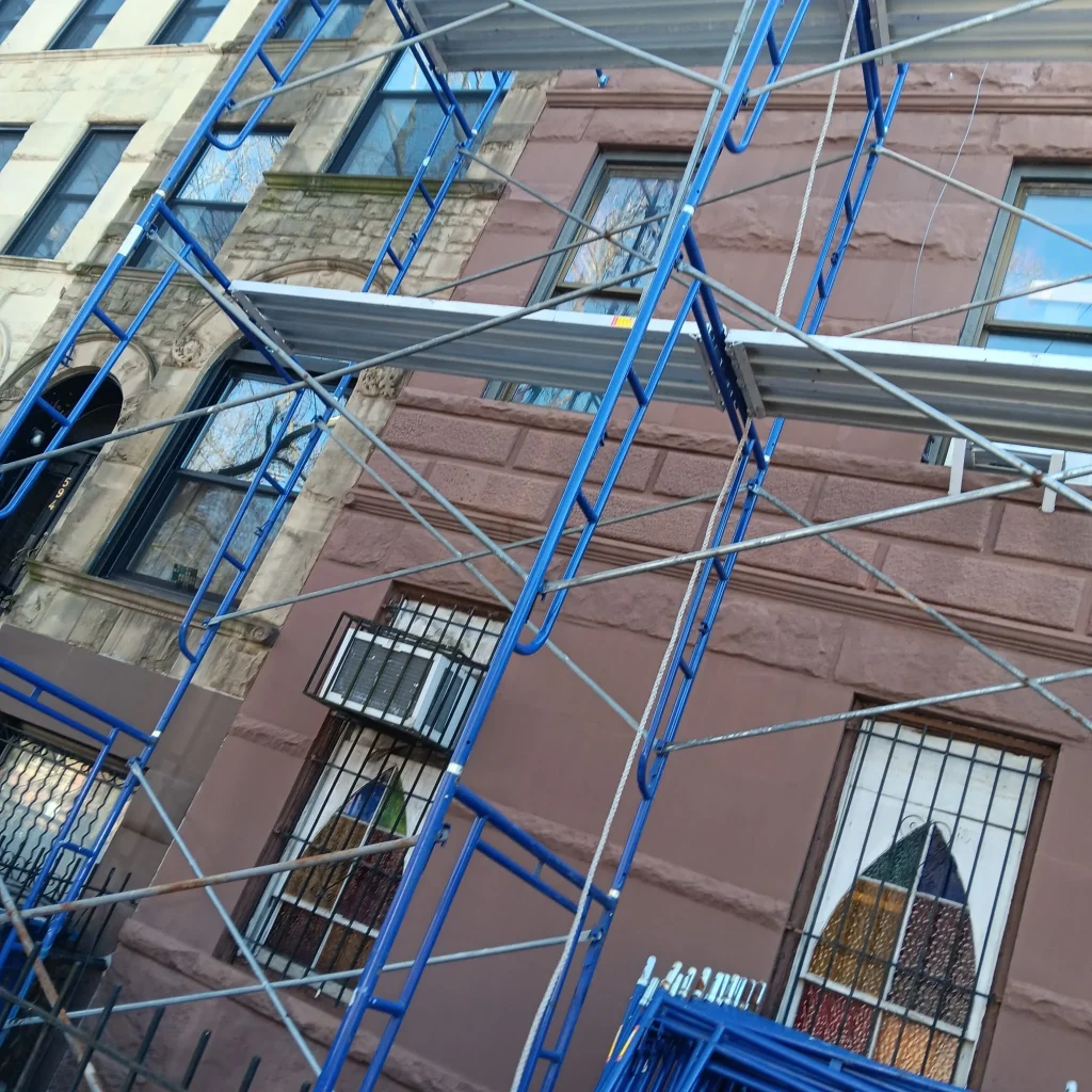 Pipe scaffolding protecting a building in Queens, with workers actively involved in the construction process