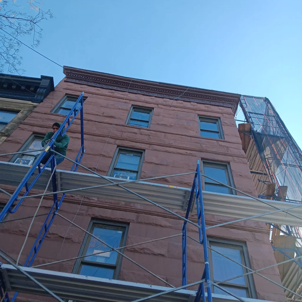 Scaffolding setup on a building in Astoria, NY, with workers on site, highlighting the importance of safety measures for scaffold workers during construction
