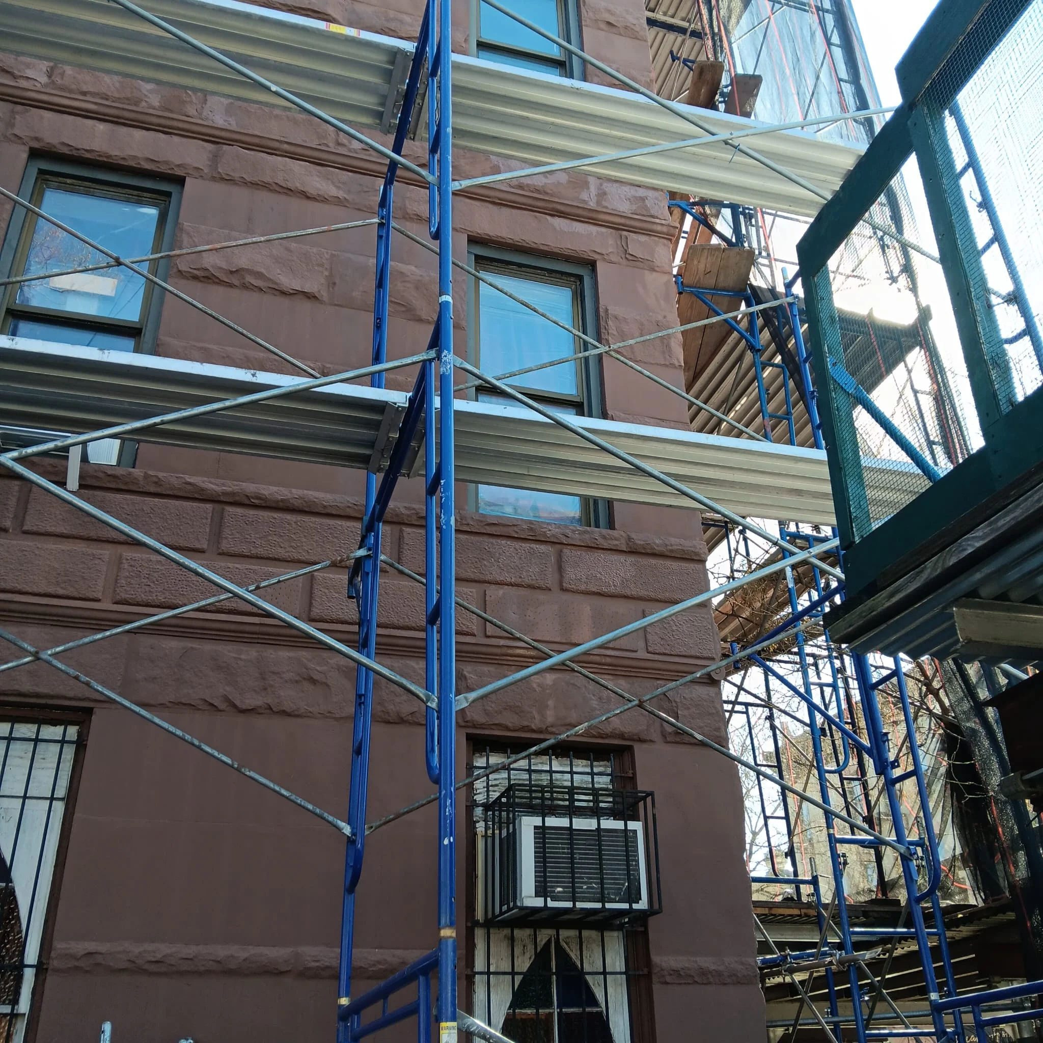 Construction scaffolding setup on residential building in Queens with safety supports