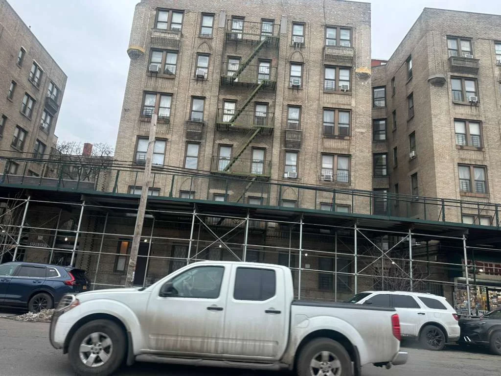 Scaffolding system surrounding a residential building, ensuring safety for workers and pedestrians during ongoing construction and maintenance