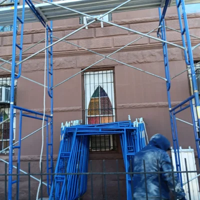 Scaffolding installation with worker assembling frame on building site in Queens NY