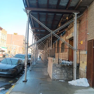 Sidewalk shed scaffolding along a building in Queens, NY, providing pedestrian safety during construction