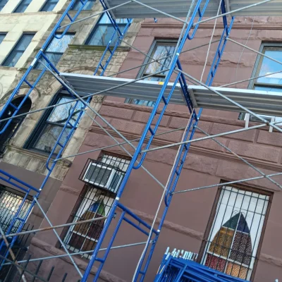 Pipe scaffolding protecting a building in Queens, with workers actively involved in the construction process