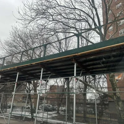 Scaffolding structure elevated above the sidewalk in Queens, NY, offering pedestrian safety while construction work is ongoing on the building above