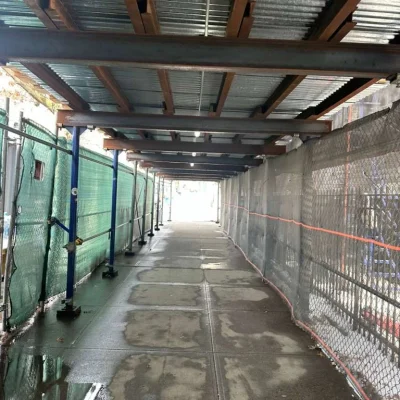 Pathway under pipe scaffolding in Queens, providing pedestrian protection during construction.